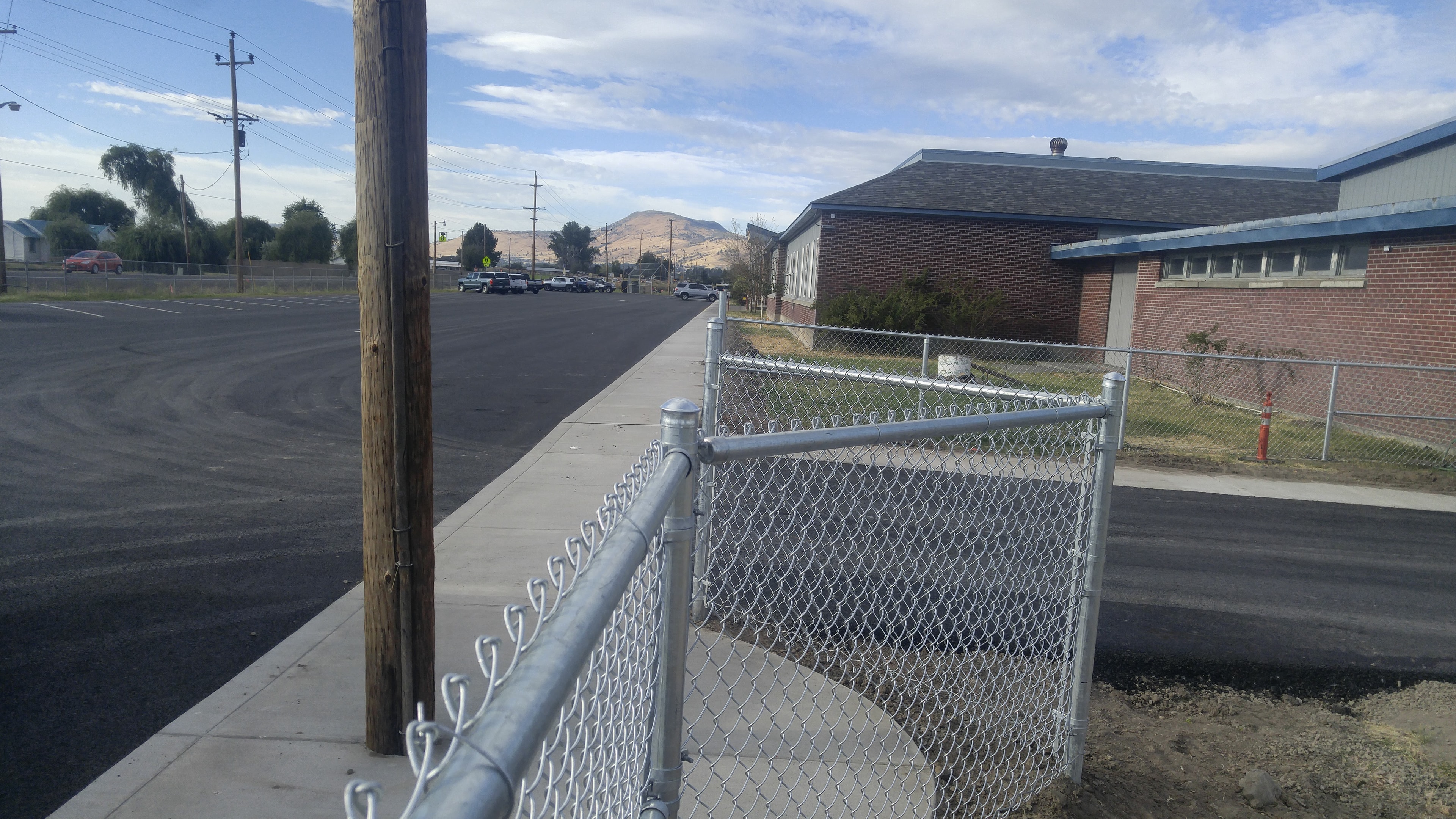 Chain link fence corner detail at a commercial school property with mountain backdrop