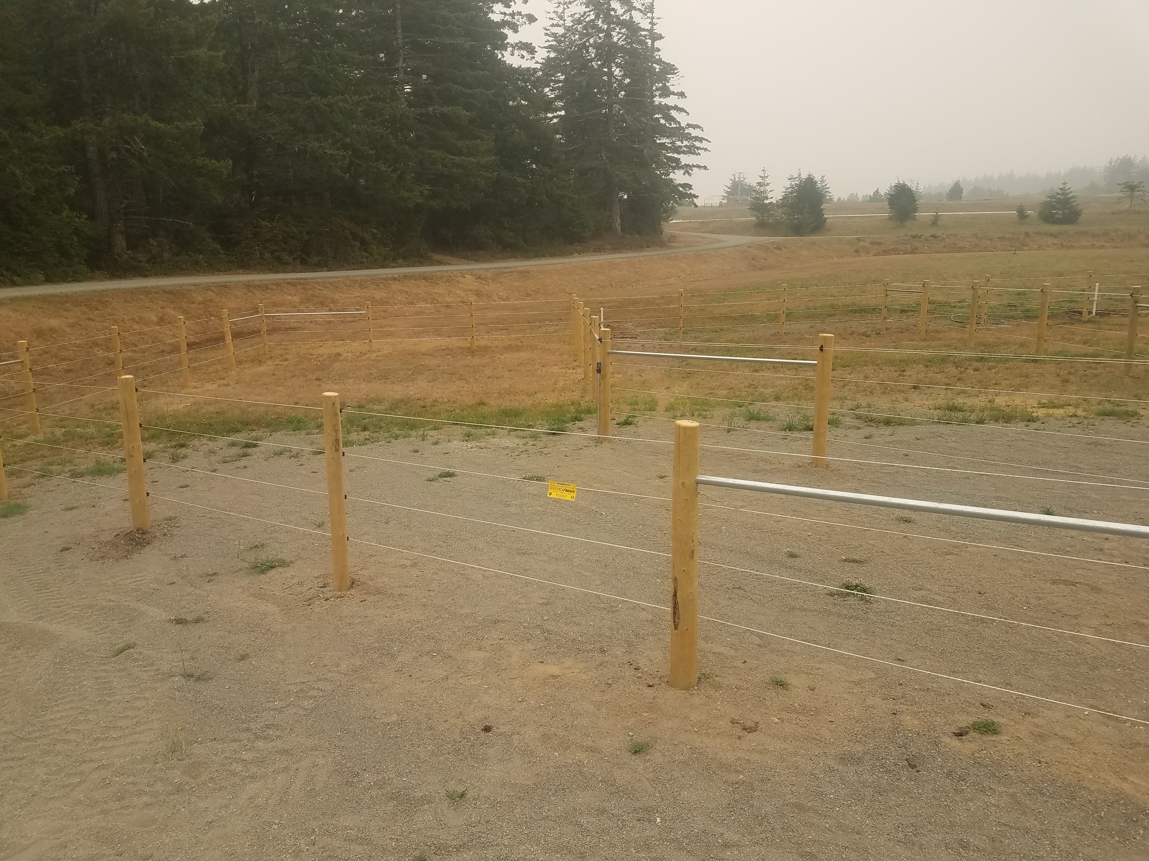 Wood post and wire pasture fence in smoky conditions