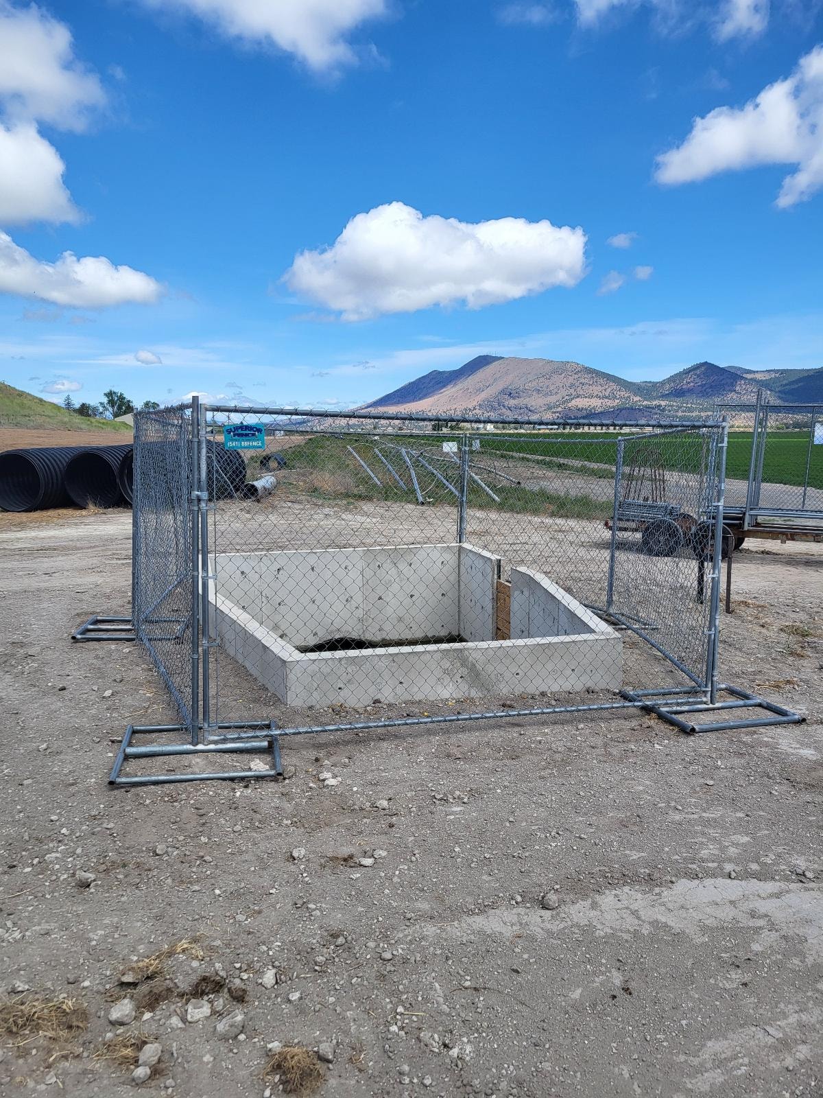 Temporary fencing enclosing a rural infrastructure project with mountain views