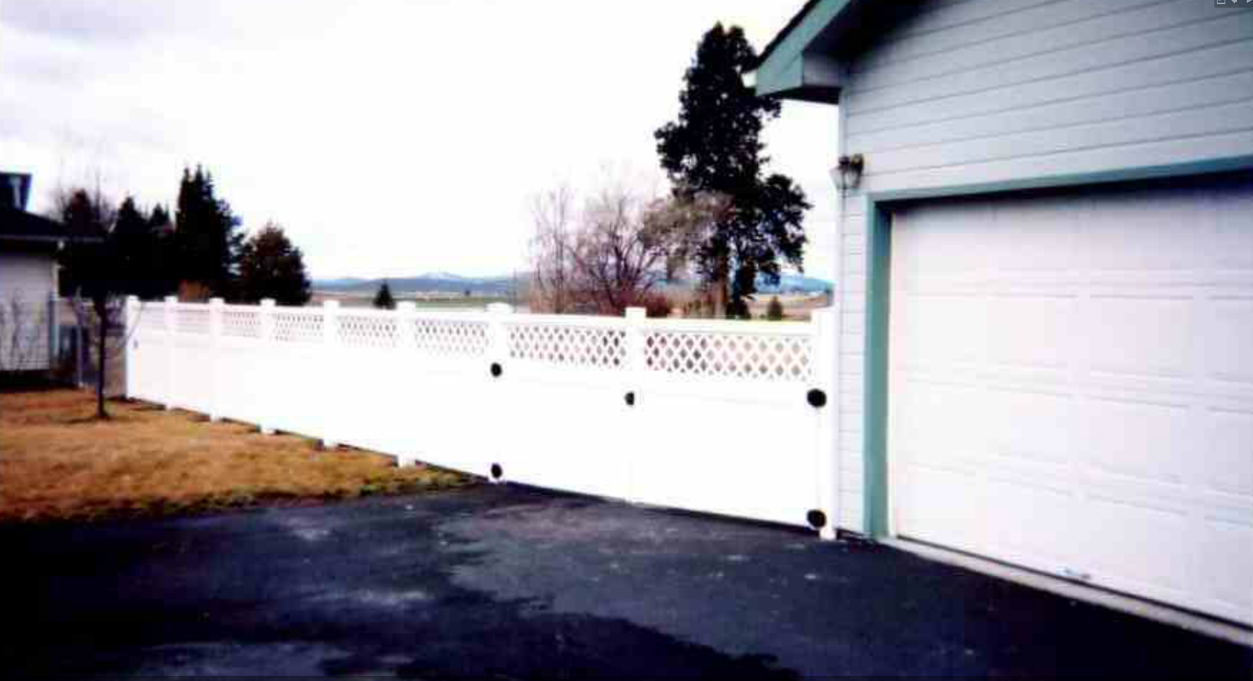 White vinyl privacy fence with decorative lattice top running along a residential driveway — Superior Fence project