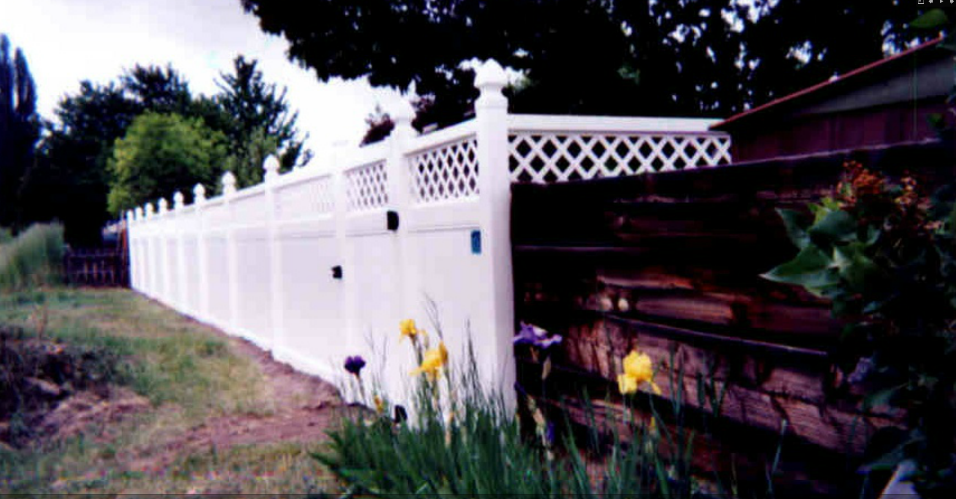 White vinyl privacy fence with lattice top and decorative post caps in a residential backyard — Superior Fence