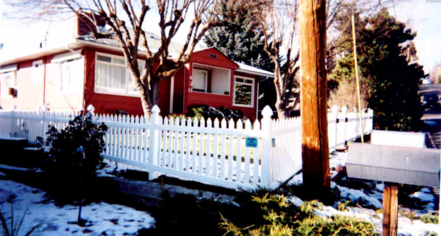 White vinyl picket fence in front of a red house in winter — Superior Fence, Klamath Falls OR